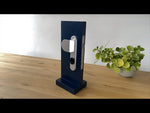 Брава за врата черна LOQED Touch Smart Lock 2S - 073916, SHELLY, LOQED Touch Smart Lock 2S B на маса с растение.